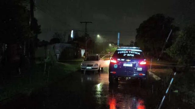Policiais armados abordam suspeito ao lado de Corsa Classic em rua de Dourados à noite