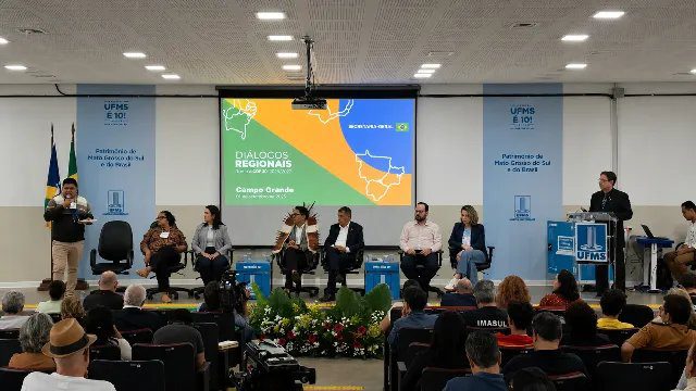 Indígenas examinam córrego seco em aldeia de MS com vegetação do Cerrado ao fundo.